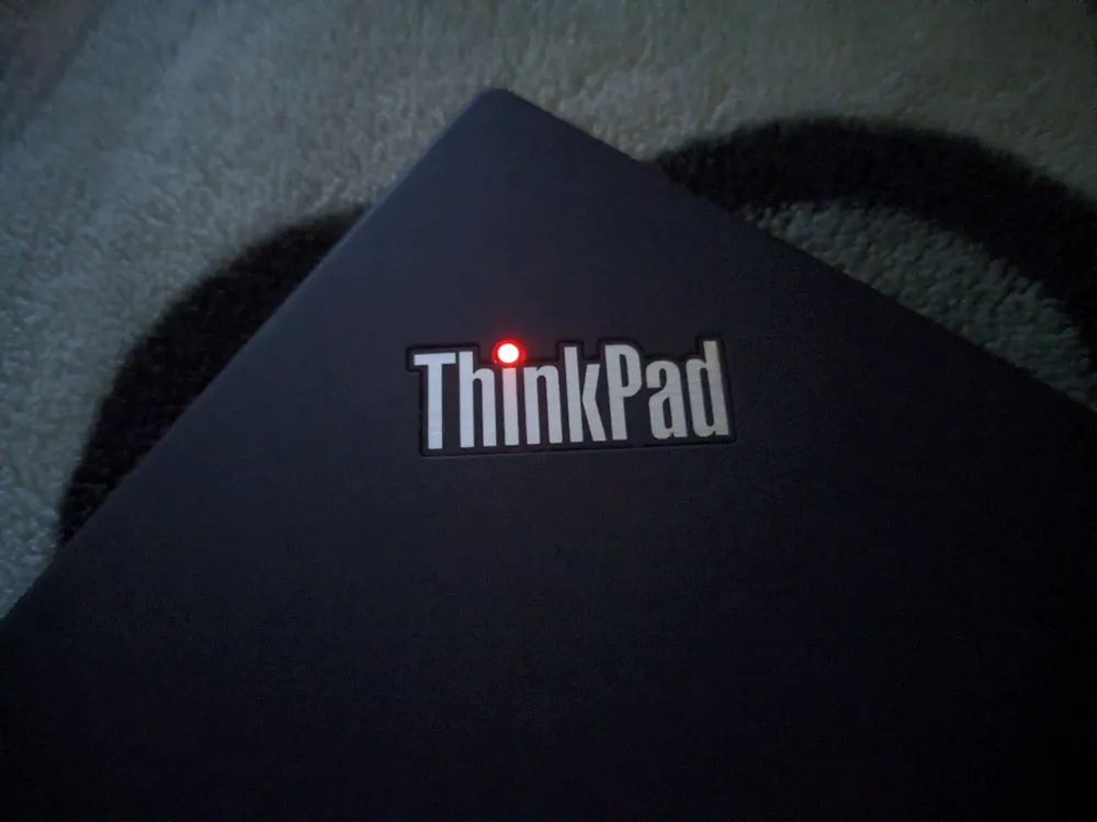 Фото логотипа ThinkPad на верхней крышке со светящейся точкой в темноте